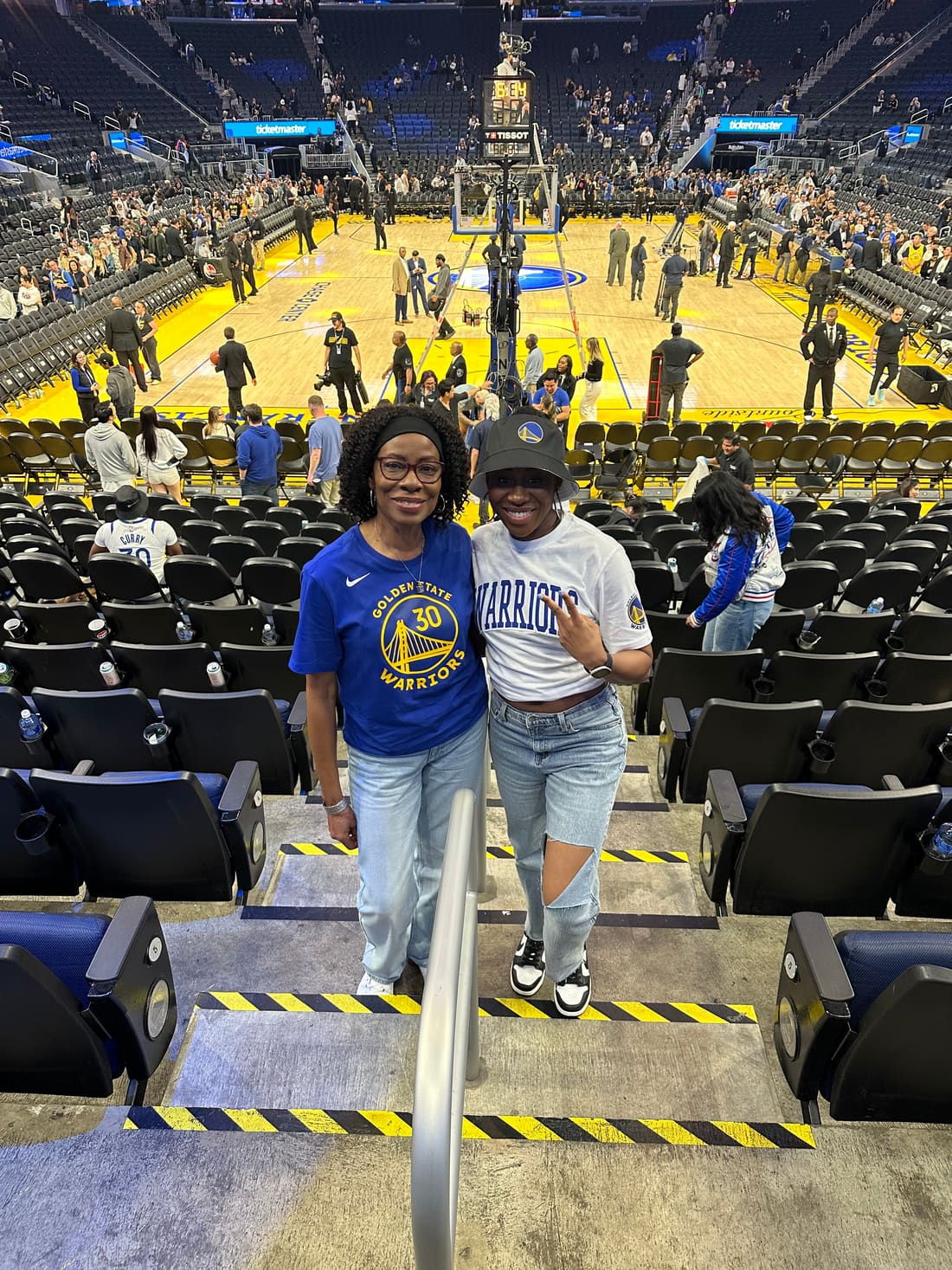Color photo of Nikki and her mom in Golden State Warriors gear at a basketball arena